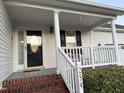 Inviting front porch with a decorative door, white railing and brick base, and a charming number sign at 254 Pedernales Dr, Smithfield, NC 27577