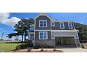 A charming two-story house with a stone foundation and integrated two-car garage at 33 White Azalea Way, Homesite 80, Benson, NC 27504