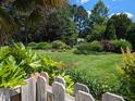 Manicured backyard featuring lush lawn, mature trees, and colorful garden beds offering serene outdoor living at 3708 Wesley Ridge Dr, Apex, NC 27539