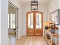 Elegant foyer featuring hardwood floors, double glass doors, stylish light fixture, and decorative table at 3901 Laurel Creek Ln, Wake Forest, NC 27587