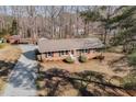 An aerial view of a brick single-story home with a gravel driveway and mature trees at 4508 Regis Ave, Durham, NC 27705