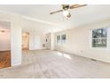 Spacious living room with neutral carpet, white walls, a ceiling fan and multiple windows at 4508 Regis Ave, Durham, NC 27705