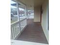 Covered front porch that extends the length of the home with white rails and wood stained flooring at 614 Oak St, Burlington, NC 27215