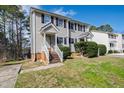 Two-story townhouse featuring light siding, dark shutters, a brick foundation, and landscaped yard at 6221 Tributary Dr, Raleigh, NC 27609
