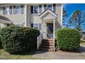 The front door is accented with decorative bushes and white trim in this quaint unit at 6225 Tributary Dr, Raleigh, NC 27609