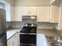 Clean kitchen featuring white cabinets, stainless steel appliances, and a gray backsplash at 6225 Tributary Dr, Raleigh, NC 27609