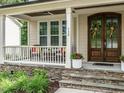 Inviting front porch with stone accents, elegant front door and a cozy seating area at 730 Toms Creek Rd, Cary, NC 27519