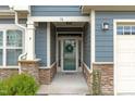 Close-up of entryway with decorative door, stone supports, and well-manicured landscaping at 74 Powderhorn Pt, Garner, NC 27529