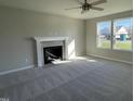 Spacious living room featuring neutral carpet, a fireplace with a mantle, and abundant natural light from two windows at 91 Lotus Ave, Smithfield, NC 27577