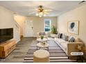 A staged living room with a neutral palette, striped rug, and ceiling fan at 910 Savin Lndg, Knightdale, NC 27545
