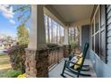 Inviting covered front porch with rocking chairs and stone supports with mature trees in the distance at 105 Anderson Park Dr, Youngsville, NC 27596