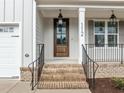 Inviting front porch features brick steps, metal railings and a wood front door at 112 Pointe Park Cir, Holly Springs, NC 27540