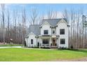 Inviting two-story white farmhouse with a covered front porch, rocking chairs, and lush green lawn at 1124 Westridge Rd, Rougemont, NC 27572