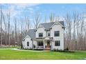 Inviting two-story white farmhouse with a covered front porch, rocking chairs, and lush green lawn at 1124 Westridge Rd, Rougemont, NC 27572