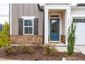 Inviting front entrance with stone accents, complemented by a blue door and well-maintained landscaping at 1201 Canary Pepper Dr, Durham, NC 27713
