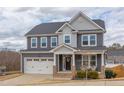 Charming two-story home featuring a two-car garage, inviting front porch with seating and beautiful grey siding at 1204 Castlestone Ln, Knightdale, NC 27545