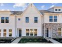 Charming exterior of a modern townhouse with a white facade, black door, and lush landscaping at 1430 Cooper St, Sanford, NC 27330