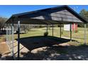 A metal carport is built to protect vehicles from the outdoor elements, on a grass and gravel lot at 148 Baptist Church Rd, Henderson, NC 27537