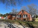 Side view of a charming red brick house with black shutters and well maintained lawn and landscaping at 148 Baptist Church Rd, Henderson, NC 27537
