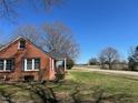 Side view of a red brick home with a covered porch and a well-maintained lawn at 148 Baptist Church Rd, Henderson, NC 27537