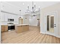 Spacious kitchen featuring stainless steel appliances, white cabinets, a center island, and a sleek, modern chandelier at 149 Amber Rd, Timberlake, NC 27583