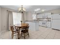 Bright eat-in kitchen with white cabinets, stainless steel appliances, chandelier, and a wooden table with four chairs at 1613 Bulon Dr, Cary, NC 27518