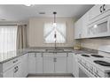 A well-lit kitchen features white cabinets, granite countertops, stainless steel appliances, and tile flooring at 1613 Bulon Dr, Cary, NC 27518