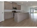 Modern kitchen with a large island, granite countertops, stainless steel appliances and wood grain floors at 210 Cason Dr, Gibsonville, NC 27249