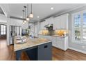 Bright kitchen featuring a large island with marble countertop, white cabinets, and stainless steel appliances at 2912 Oakley Woods Ln, Apex, NC 27539