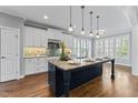 Bright kitchen featuring a large island with marble countertop, white cabinets, and stainless steel appliances at 2912 Oakley Woods Ln, Apex, NC 27539