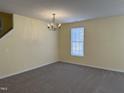 Cozy living room with plush carpeting, light-filled window, and modern lighting fixture, creating a welcoming space at 316 Arbor Greene Dr, Garner, NC 27529