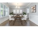 Elegant dining room featuring wainscoting, modern chandelier, plantation shutters, and plenty of natural light at 5072 Aspen Meadow St, Raleigh, NC 27616