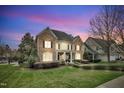 Dusk view of a manicured two-story home with stone and siding, as well as pristine landscaping at 601 Ballad Creek Ct, Cary, NC 27519