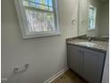 Bathroom showcasing a granite countertop vanity, framed mirror, window views, and wood-look vinyl flooring at 95 Tulipfield Way, Benson, NC 27504
