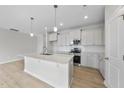 Open kitchen with stainless steel appliances, white cabinetry, island, and pendant lighting at 96 Ripple Way # 316, Clayton, NC 27520