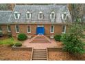 Aerial shot of a brick home featuring a detailed roof, dormer windows, and brick stairs leading up to a blue door at 10726 Trego Trl, Raleigh, NC 27614