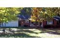 Cozy red brick ranch-style home with a gray roof and front porch swing nestled among trees at 209 High House Rd, Cary, NC 27513