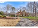 Spacious brick home with an elegant driveway, lush landscaping, and a classic architectural design under a bright blue sky at 4405 Turnberry Cir, Durham, NC 27712