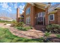 Welcoming brick home entrance with a curved brick path leading to elegant double doors and blooming flowers at 4405 Turnberry Cir, Durham, NC 27712