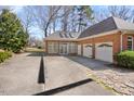 A well-maintained brick home with a spacious driveway, a three-car garage, and an attached sunroom addition at 4405 Turnberry Cir, Durham, NC 27712