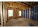 Unfinished bedroom shows exposed framing, blue sheathing, and windows, ready for customization at 6966 Doddridge Ln # 12, Cary, NC 27519