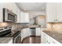 Modern kitchen featuring stainless appliances, granite countertops, and white cabinetry at 7213 Terregles Dr, Raleigh, NC 27617