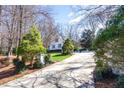 View of long driveway leading up to a white house with well-maintained landscaping and mature trees at 9700 Pentland Ct, Raleigh, NC 27614