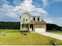 Charming two-story home featuring a combination of stone and siding with a manicured lawn at 125 Scotland Dr, Youngsville, NC 27596