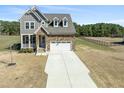 View of the two-story home with stone and gray wood, an attached two-car garage, and a driveway in the front yard at 125 Scotland Dr, Youngsville, NC 27596