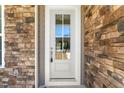 Close-up of the white front door with glass, surrounded by stone and gray siding, and a silver handle with key at 125 Scotland Dr, Youngsville, NC 27596