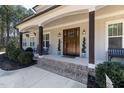 Spacious covered front porch with beautiful columns, a wooden front door, and well-maintained landscaping at 5600 Abbey Grace Ln, Wake Forest, NC 27587