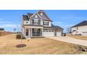 Charming home featuring a covered porch, a three-car garage, and a manicured lawn on a sunny day at 59 N Clearbrook Ct, Angier, NC 27501