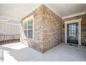 Close-up of home exterior with stone siding, covered porch, and black front door with glass panels at 1013 Restoration Dr, Durham, NC 27703