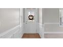 Bright foyer featuring a white door with glass, wainscoting, and hardwood flooring at 104 Stenness Ct, Apex, NC 27502